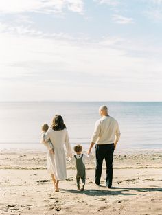 a family walking on the beach holding hands