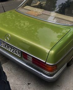 a green mercedes benz is parked on the street