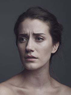 a woman with no shirt on is posing for a photo in front of a gray background