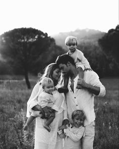 a black and white photo of a family posing in a field with their two children