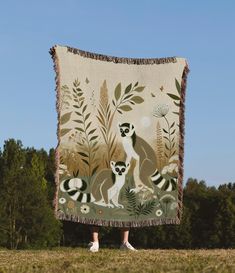 a woman standing in front of a tapestry with two lemurs and flowers on it