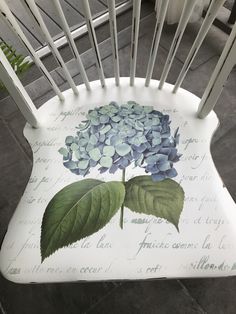 a white chair with blue hydrangeas painted on it's back and seat