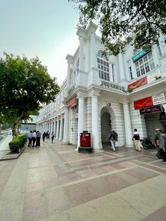 people are walking around in front of a white building