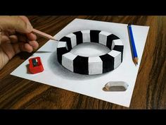 a person is drawing a black and white striped cake with a pencil on the paper