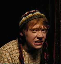 a man with red hair wearing a knitted hat and making a funny face while looking at the camera