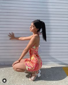 a woman squatting on the ground in front of a garage door with her hand out