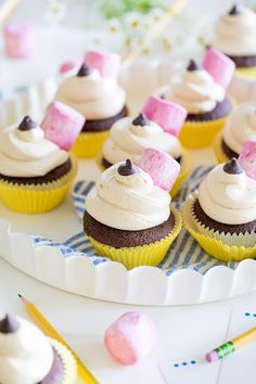 several cupcakes with white frosting and pink marshmallows on top