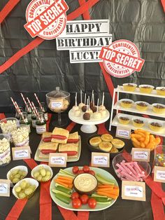 a table topped with lots of food next to a sign that says happy birthday lucky top secret