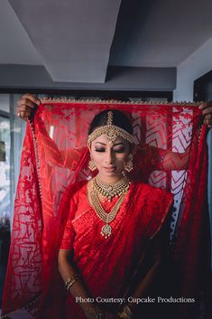 a woman in a red sari holding up a red cloth