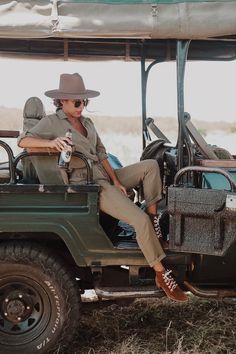 a woman sitting on the back of a green jeep with a bottle in her hand