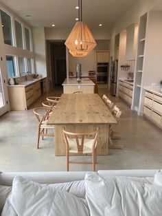 a large open kitchen and dining room with an island table in the middle, surrounded by white couches