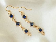 These elegant blue and gold earrings, are perfect for your special occasion! They feature sapphire blue zircon gemstones, in a high quality, 18k gold plated setting.  Product details: * 18k gold plated ear wires; Lead and nickle free * Zircon gemstones * 18k gold plated setting * Handmade, with lots of love and care! - Length:    2 inches - Width:     .25 inches ❤ You can click here to see more unique jewelry from Flutterbird: https://www.etsy.com/shop/FlutterbirdCo My goal is to provide every customer with exceptional service. Please message me if you have any questions. Thank you for supporting my small business!  Please visit my F.A.Q. and shop policy sections for additional info. Elegant Sapphire Crystal Dangle Earrings, Gold Sapphire Dangle Earrings, Gold Sapphire Drop Earrings, Sapphire Drop Crystal Earrings, Elegant Sapphire Crystal Earrings For Pierced Ears, Elegant Sapphire Crystal Drop Earrings, Elegant Sapphire Crystal Earrings, Elegant Sapphire Bridal Earrings For Gift, Blue Gold-plated Earrings For Wedding