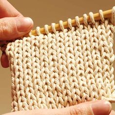 a hand holding a piece of yarn with a wooden needle