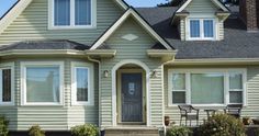 a house that is painted green and has white trim on the front door, windows, and porch