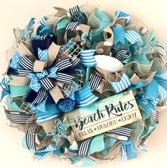 a wreath made out of blue and white ribbons with a beach rules tag on it