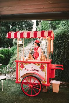 a red and white cart sitting on top of a lush green field