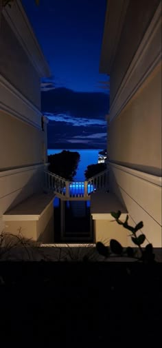 an open door leading to a balcony at night with lights on and trees in the foreground