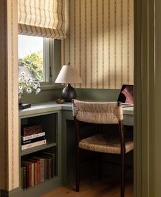 a chair sitting in front of a window next to a desk with a lamp on it