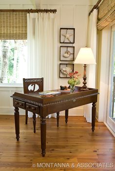 a wooden table sitting on top of a hard wood floor next to a lamp and window