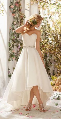 a woman in a white wedding dress is posing for the camera