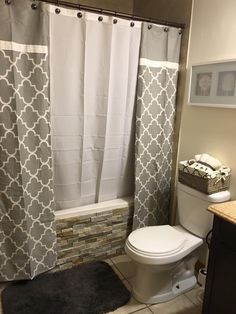 a white toilet sitting next to a bath tub in a bathroom under a shower curtain