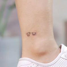 a small tattoo on the ankle of a woman's foot, with two cats