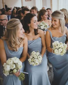 the bridesmaids are all laughing together in their blue gowns and bouquets