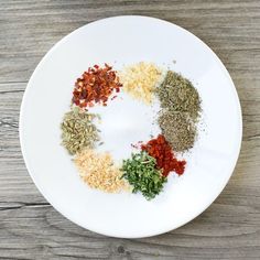 a white plate topped with spices and seasonings on top of a wooden table next to a knife