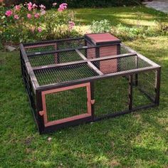 three cages are sitting on the grass in front of some bushes and flowers, one is empty