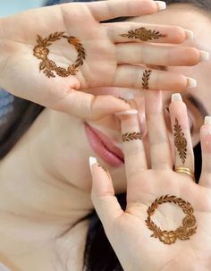 a woman holding her hands up to her face with hendi tattoos on their palms