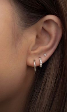 a woman wearing an earring with two small diamonds on the top of her ear