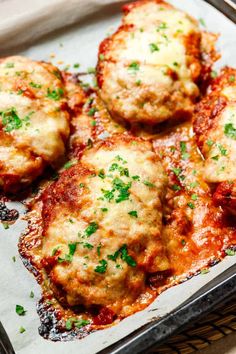 meatballs covered in marinara sauce and parsley on top of a baking sheet