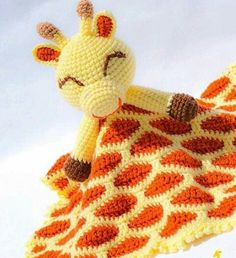 a crocheted giraffe laying on top of a blanket