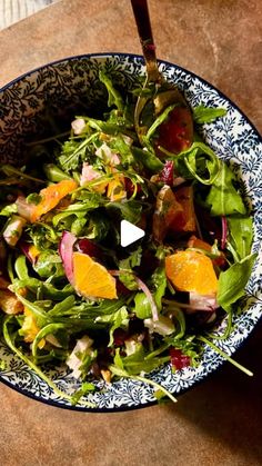 a blue and white bowl filled with salad on top of a table