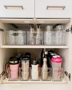 an organized kitchen cabinet filled with containers and cups