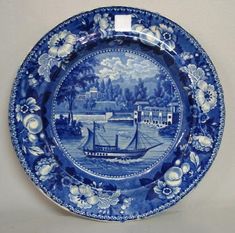 a blue and white plate with an image of a boat in the water on it