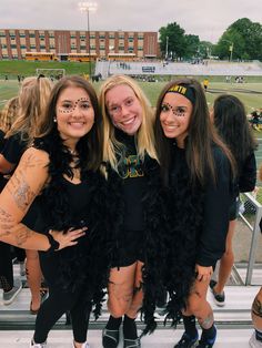 three girls with face paint on their faces posing for the camera at a football game