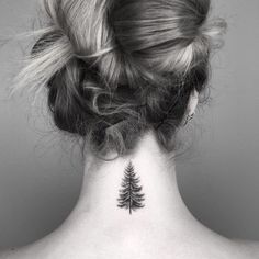 a woman's back neck with a small pine tree tattoo on her left side