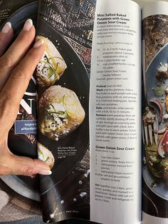 a person is holding a plate with food on it and an open cookbook in front of them