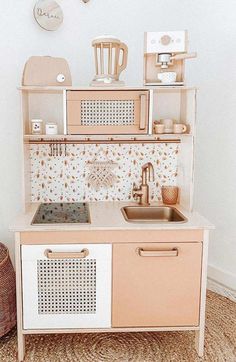 a wooden toy kitchen with sink, stove and cupboards in it's display area