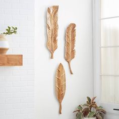 three wooden leaves are hanging on the wall next to a potted plant and window