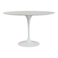 an oval marble dining table with white legs and a round base, viewed from the front