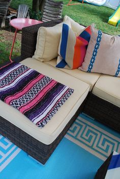 a couch with colorful pillows on it sitting in the grass