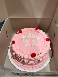 a pink cake in a cardboard box with the number 22 on it's side