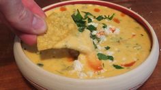 a hand dipping a tortilla chip into a bowl of quesadilla soup