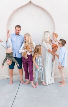 a group of people standing in front of a white wall with an arch on it