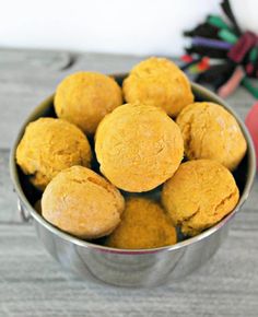 a metal bowl filled with muffins on top of a wooden table