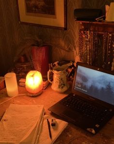 an open laptop computer sitting on top of a wooden table next to a lit candle