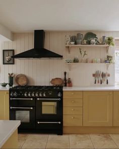 a black stove top oven sitting inside of a kitchen next to yellow cabinets and counter tops