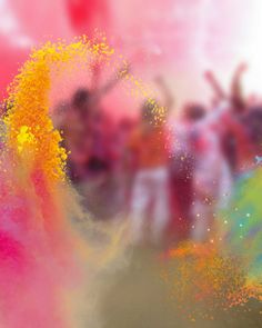 blurry photograph of people dancing with colored powder